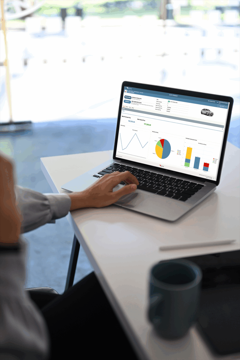 A person interacting with a laptop displaying the Bynx stock management application, showing charts, graphs, and financial data on the screen.
